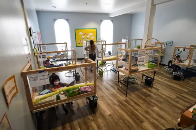 An instructor walks through the room as students from different schools and in different grades follow their online classes from desks separated by plastic barriers at the Westwood STAR Tutoring & Enrichment Center on September 10, 2020 in Los Angeles, California