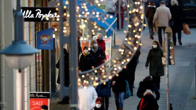 People with protective face masks walk beside Christmas themed lights at Schloss Strasse shopping street, amid the coronavirus disease (COVID-19) outbreak in Berlin