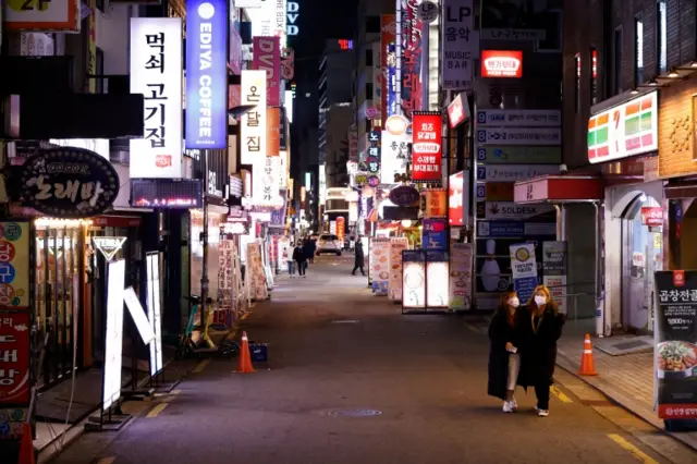 People walk down an empty street in Seoul