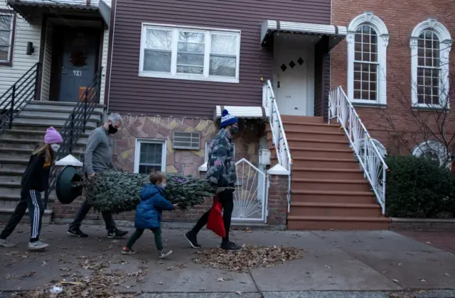 A family in New York carry a Christmas tree