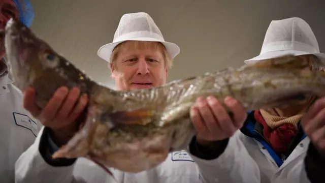 Boris Johnson holds a fish