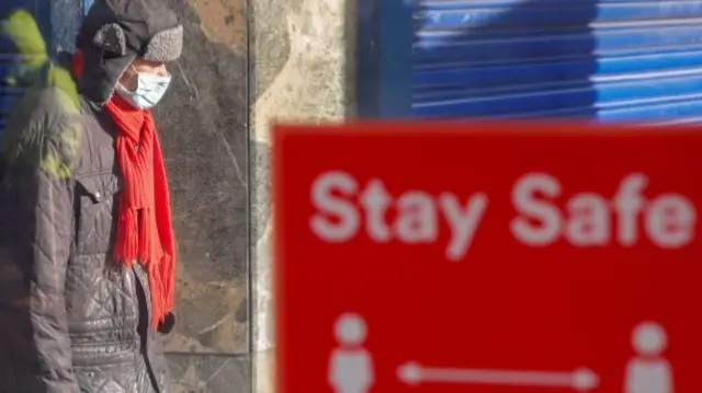 Man in mask and 2m sign