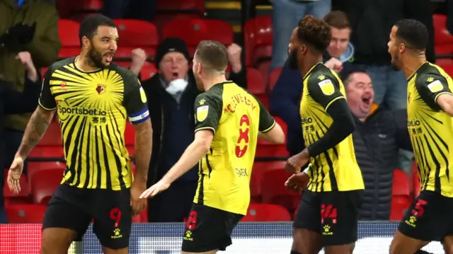 Watford players embrace captain Troy Deeney after his goal v Brentford