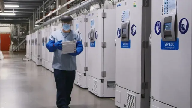 A worker passes a line of freezers holding coronavirus disease (COVID-19) vaccine candidate BNT162b2 at a Pfizer facility in Puurs, Belgium in an undated photograph.