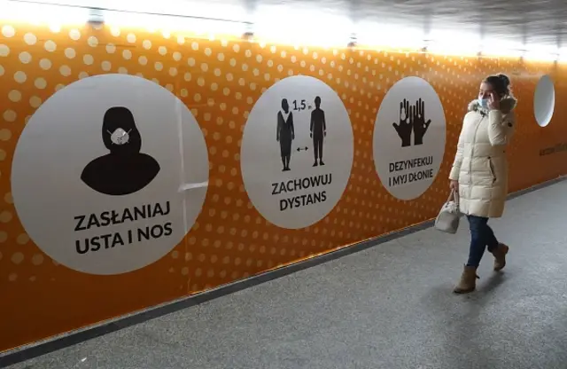 A woman walks wearing a face mask along a corridor with billboards warning how to protect from the coronavirus COVID-19 infection in Warsaw, Poland, on November 7, 2020