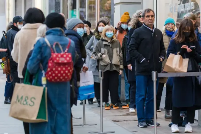 Shoppers queue outside shops in Oxford Street, London