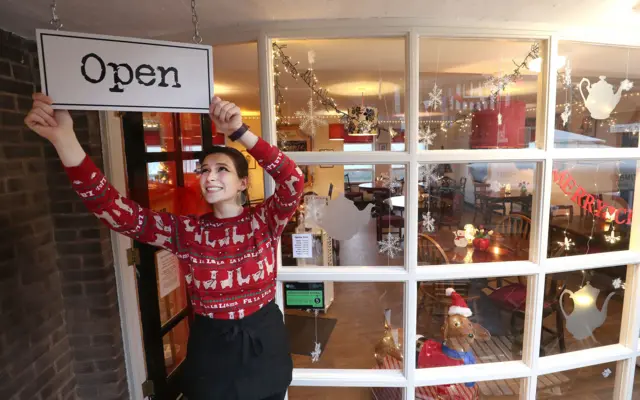 Harriet Henry, manager of The Tea Room in Knutsford, hangs an open sign outside her cafe