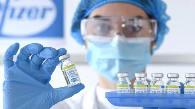 A woman holding a bottle of vaccine