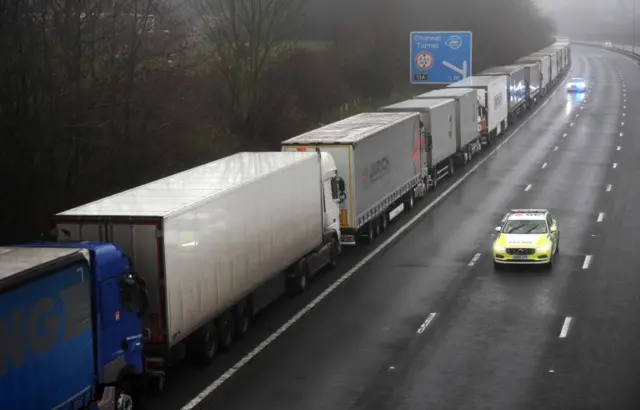 A police car patrols lorries headed to the Port of Dover along the M20 motorway in Kent