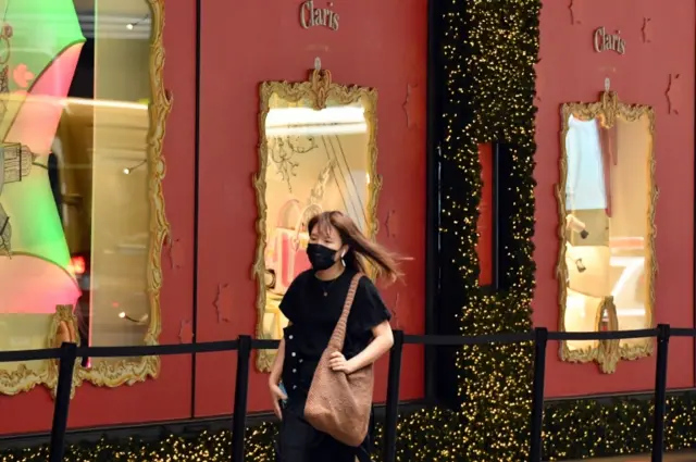 A woman walks through Sydney wearing a mask