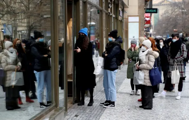 Customers queue in front of a reopened shop during the coronavirus outbreak in Prague