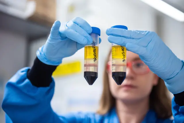 A scientist holding the Oxford vaccine