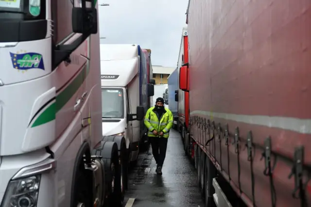 A driver walks between vehicles as they queue trying to enter the Port of Dover