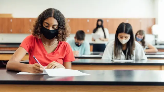 Students sitting tests in class, wearing face masks