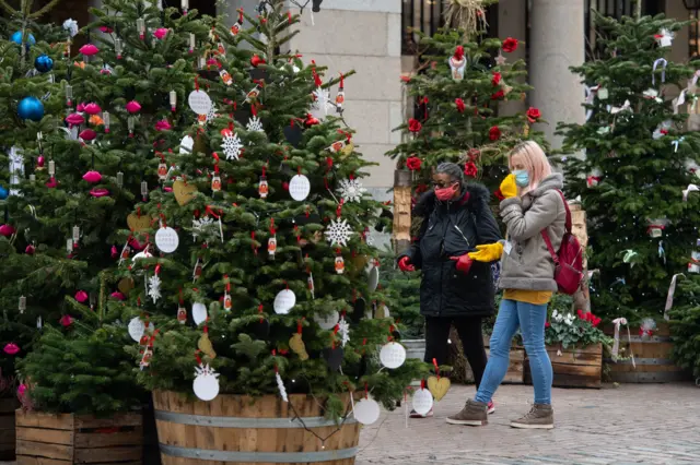 Shoppers in masks with Christmas Tree