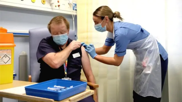 Deputy charge nurse Katie McIntosh administers the first of two vaccine jabs to clinical lead of outpatient theatres Andrew Mencnarowski, at the Western General Hospital in Edinburgh