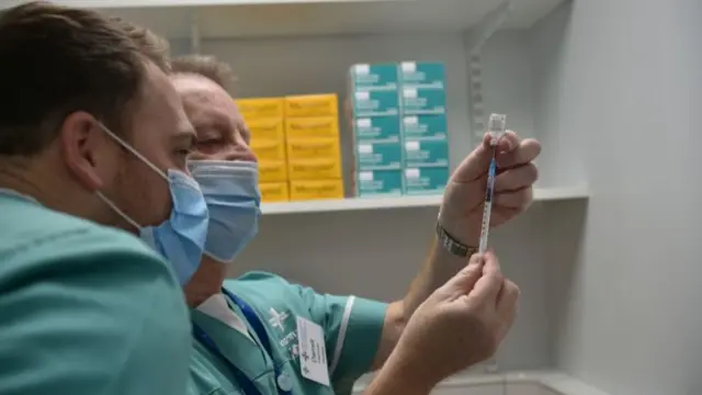 Two members of medical staff check the Pfizer/BioNTech Covid-19 vaccine jab