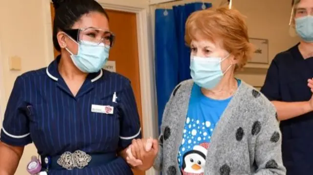 Margaret Keenan, 90, walks with nurse May Parsons (left)