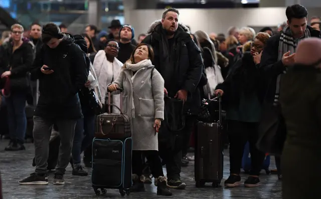 Commuters wait for trains at London Euston station