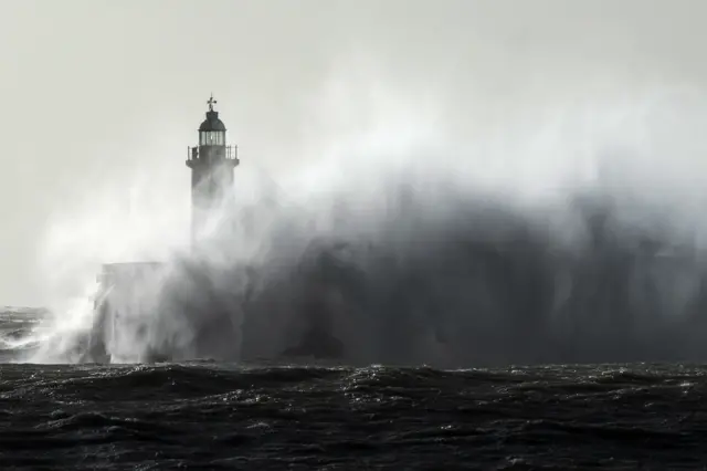 A lighthouse in Newhaven, East Sussex, is hit by waves.