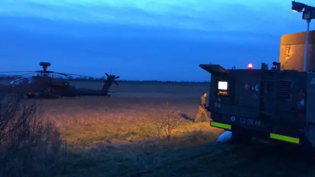 Engineers work on grounded Apache helicopter