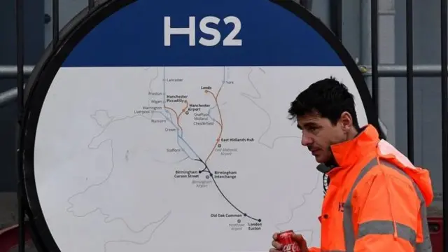 A worker walking past an HS2 map