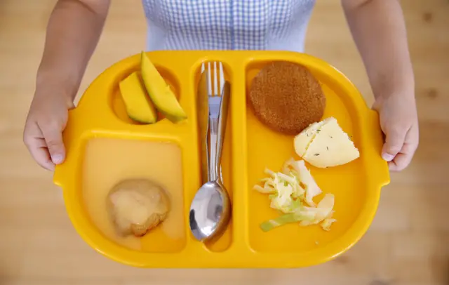 A schoolchild holding a meal tray