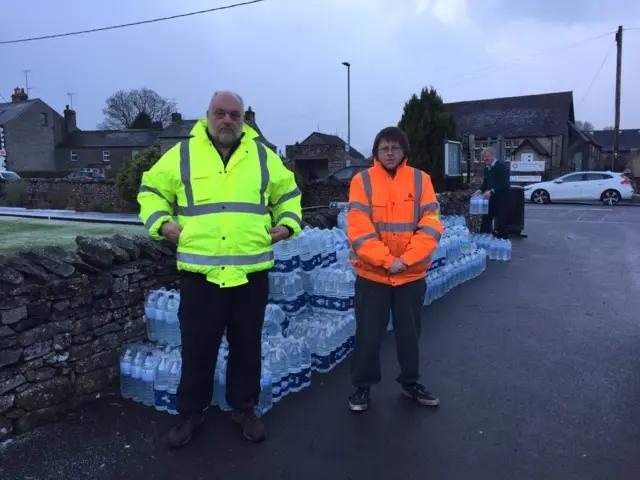 Two men at a water collection station in Shap