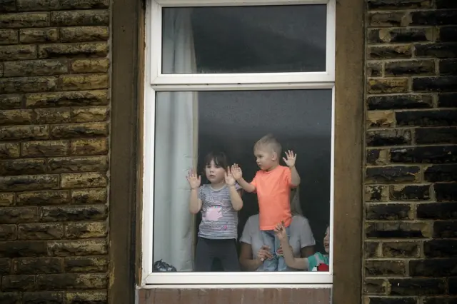 Young children watch the weather and soldiers helping to shore up flood defences