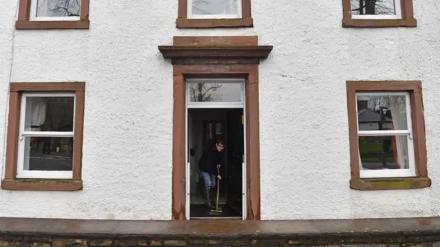 A woman sweeps water out of a residential building in Appleby, northwest England, on February 10, 2020