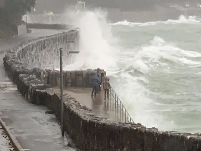 People on wall next to sea