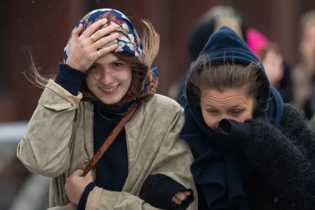 Women huddle against wind