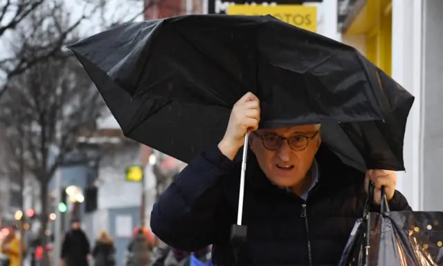 man holds broken brolly over his head