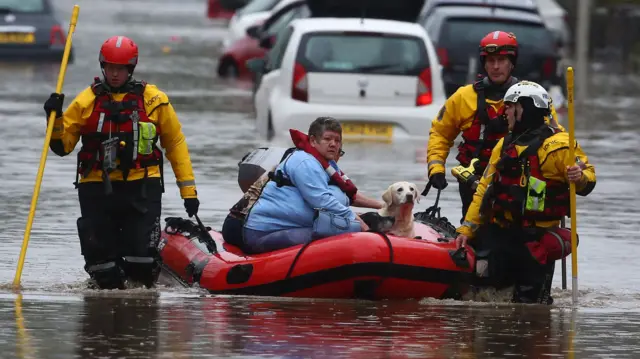 A lady and her dog are evacuated from the flooding in south Wales