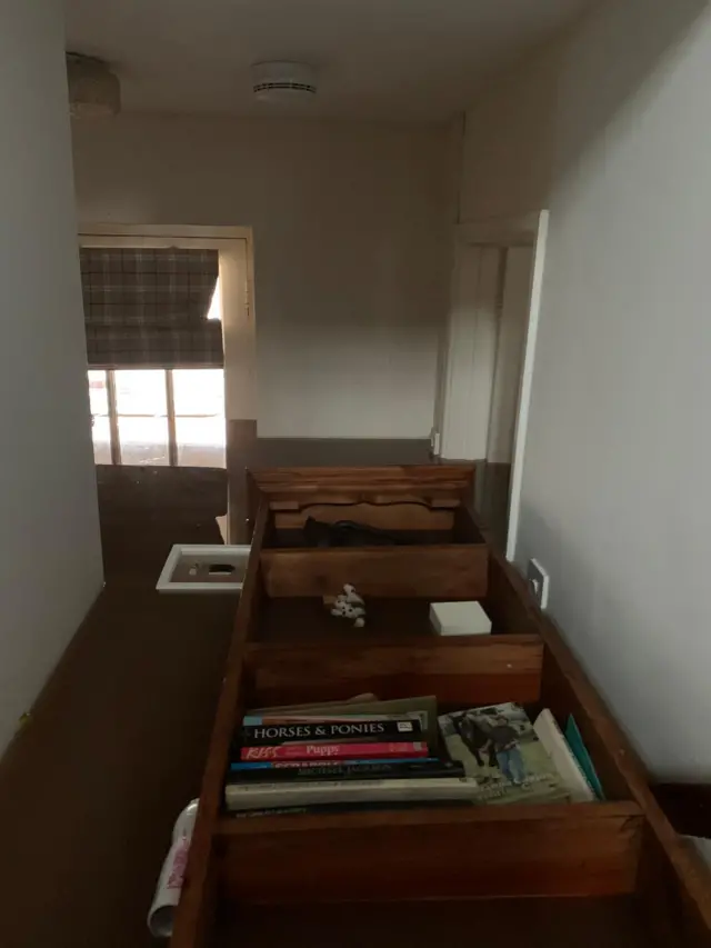 Bookcase floating in floodwater inside a house