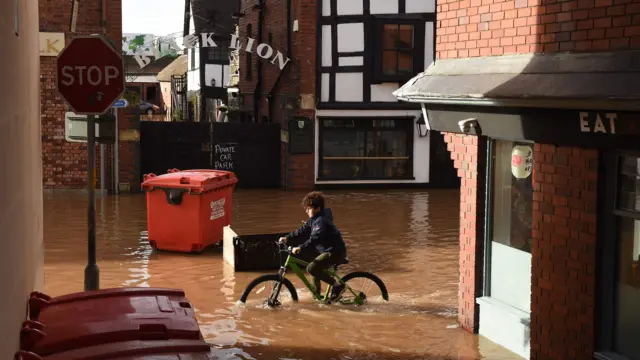 A boy cycling through the water in Hereford