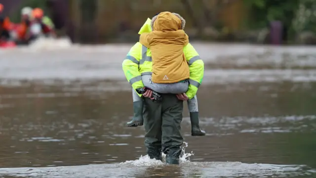 Man carries a child through floodwater