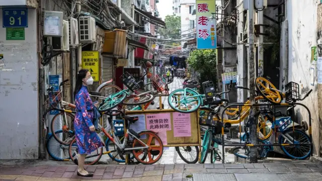 Woman with face mask on walking past masses of bikes