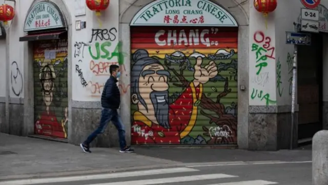 A man, wearing a respiratory mask, walks past a shuttered restaurant in the Paolo Sarpi district (Milan's Chinatown) on February 25, 2020 in Milan, Italy.