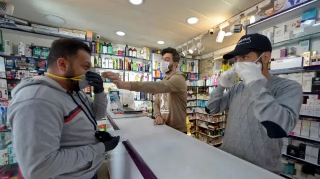 An Iraqi man checks a protective mask at a pharmacy on February 25, 2020 in the holy Iraqi city of Najaf, where the first case of coronavirus COVID-19 has been documented in Iraq