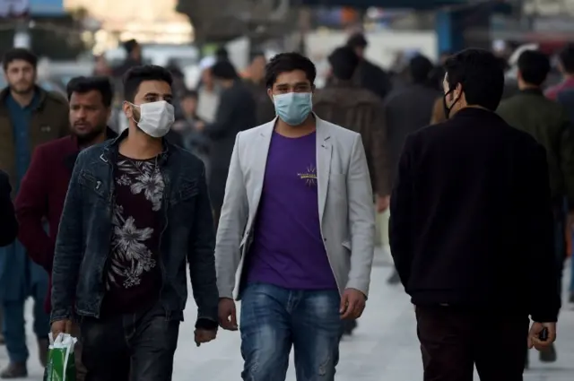 Men wearing protectives facemasks walks at the Shahr-i-Naw area in Kabul on February 25, 2020.