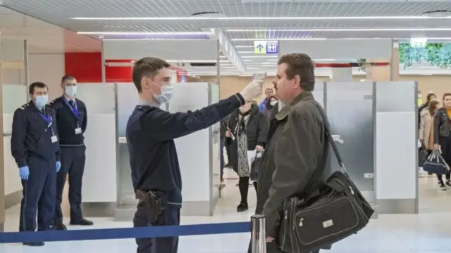 Immigration officers perform a thermal scan on passengers arriving at the airport of Chisinau, Moldova, 25 February 2020.