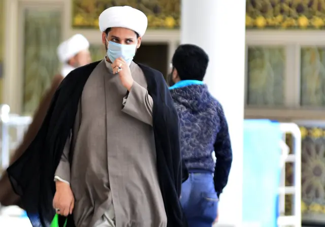 An Iraqi cleric wearing a protective mask