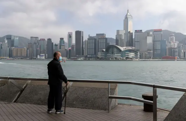 A masked man looking out Victoria Harbour in the very quiet and empty Tsim Sha Tsui Promenade