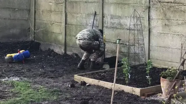 Soldier kneeling down in the ground of a garden