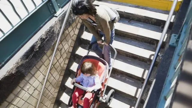 A woman taking a pram down stairs