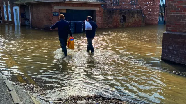 People walking into floodwater