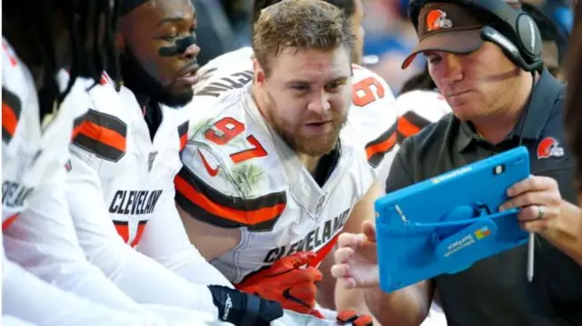 Cleveland Browns American football players look at a Microsoft Surface tablet during a game against the Arizona Cardinals