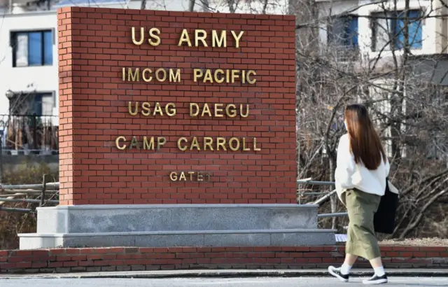 A woman walks past the main gate of US Army Camp Carroll in Chilgok, about 30 kilometres north of Daegu,