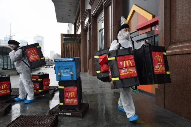 McDonald's workers wear protective suits as they deliver food in Wuhan - the city where the virus emerged late last year.